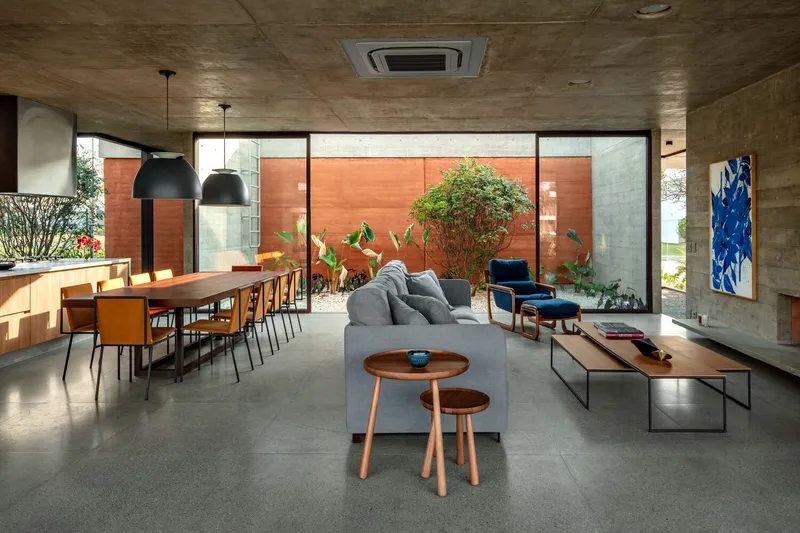 Open plan living and dining room with board-formed concrete ceiling and courtyard beyond