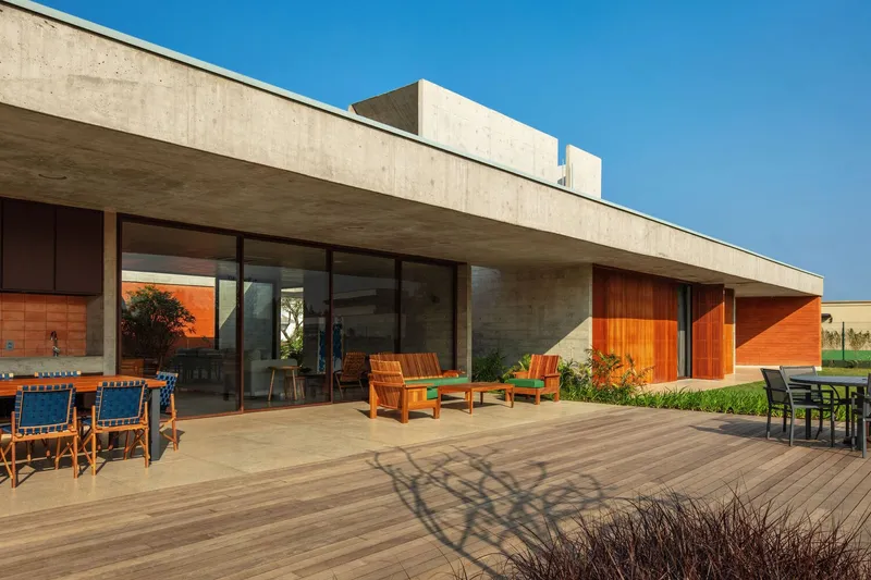 Timber deck terrace extending from glass-walled living space beneath a deep concrete cantilevered roof