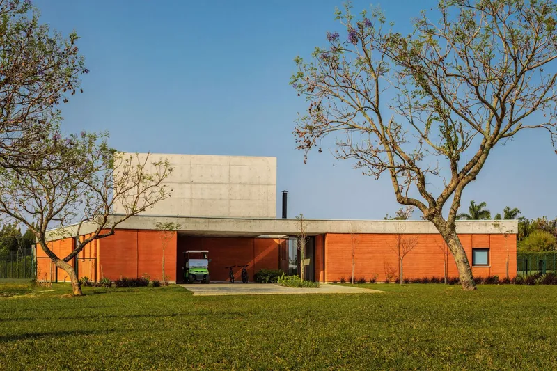 Long view of the residence across a lawn with sparsely leaved trees in afternoon sunlight