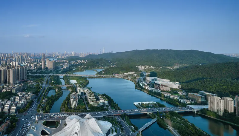 Drone perspective of the institutional campus along the waterfront with terraced buildings and curved white roof