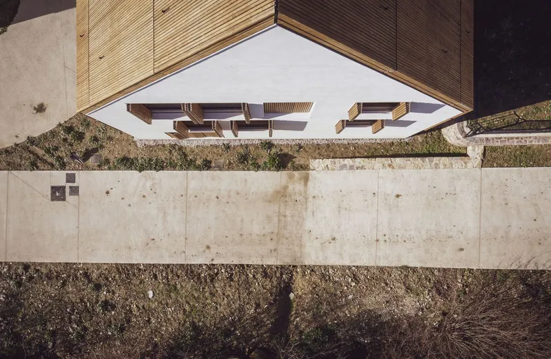 Aerial view of the gabled roof with vertical timber cladding above a concrete retaining wall