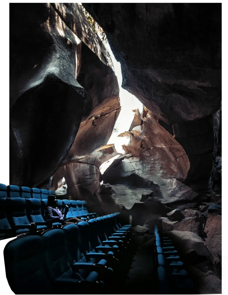 Blue theater seating installed inside a natural cave chamber lit by daylight