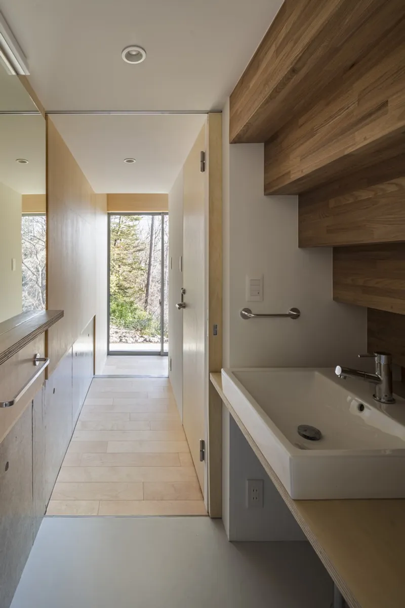 Bathroom corridor with timber stair treads and a doorway opening to the landscape beyond