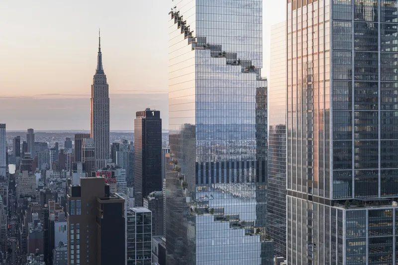 Stepped glass facade of highrise tower with diagonal notches catching warm light at sunset