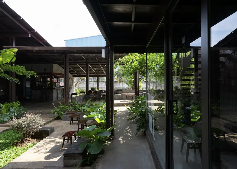 Covered terrace with dark timber columns and exposed rafters looking onto the garden courtyard in bright daylight