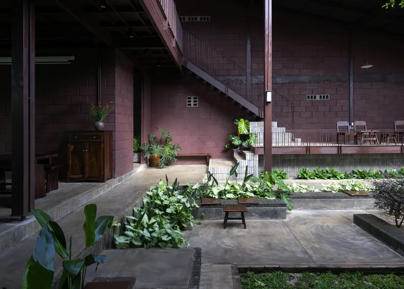 Interior courtyard with raised planted beds, concrete block walls, steel staircase, and mezzanine dining level