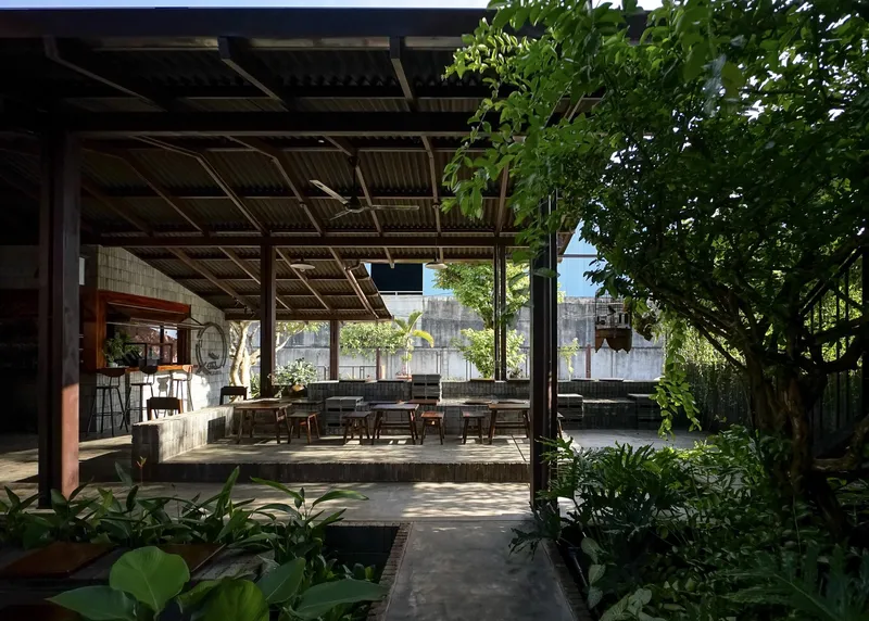 Covered terrace overlooking a courtyard garden with mature trees filtering afternoon light