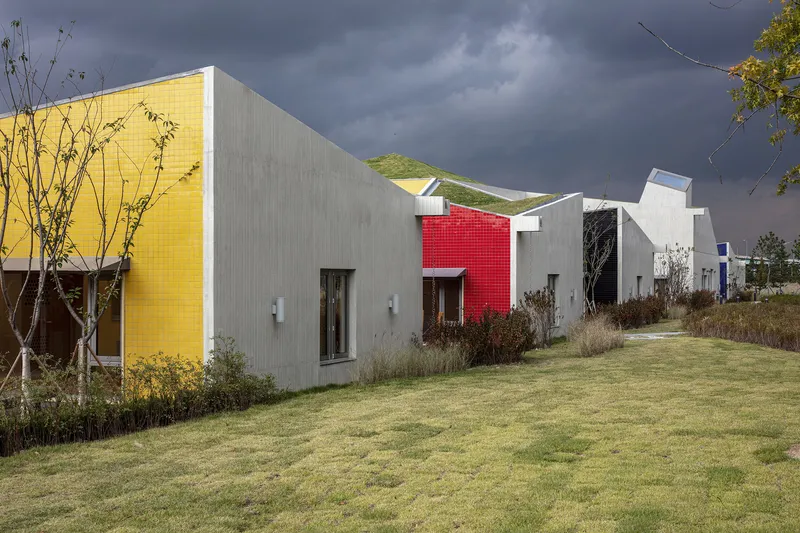 Row of colored tile pavilions with yellow, white, and red facades beneath a stormy grey sky