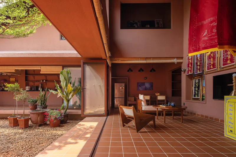 Covered terrace with terracotta tile flooring overlooking gravel courtyard with potted plants and afternoon shadows