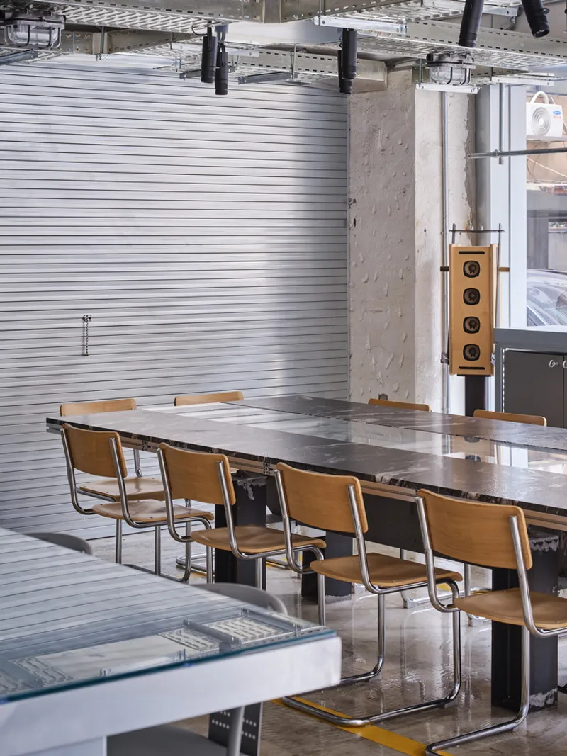 Close-up of marbled stone tabletop with wooden cantilever chairs along a concrete column