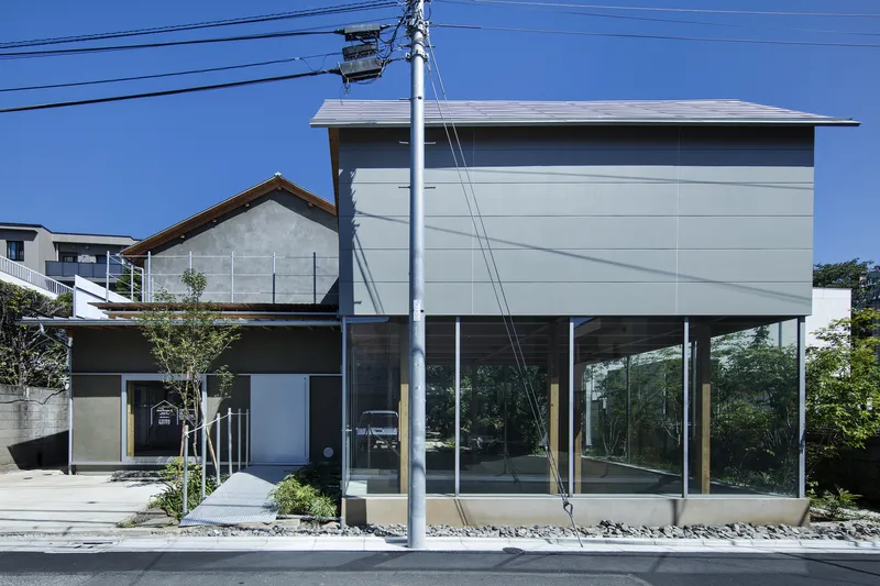 Two-story facade showing upper panel volume elevated above glazed ground floor beneath overhead power lines