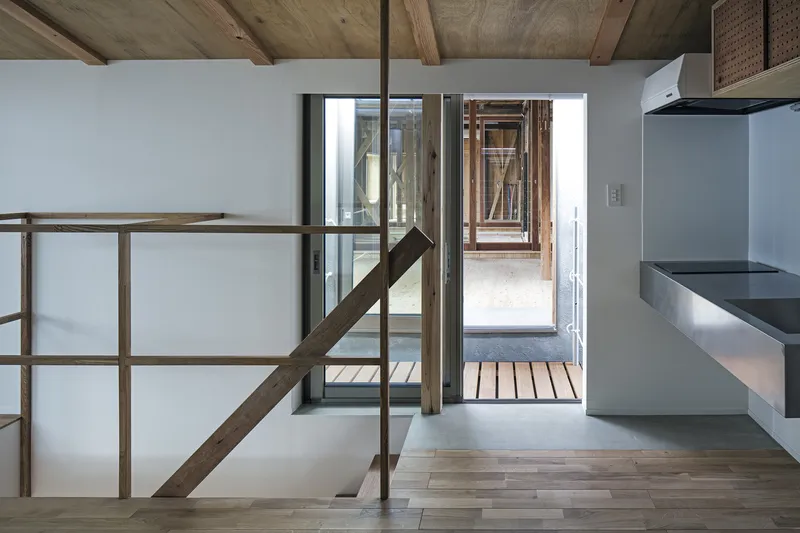 View toward glazed courtyard from upper level with timber handrail and exposed rafters overhead