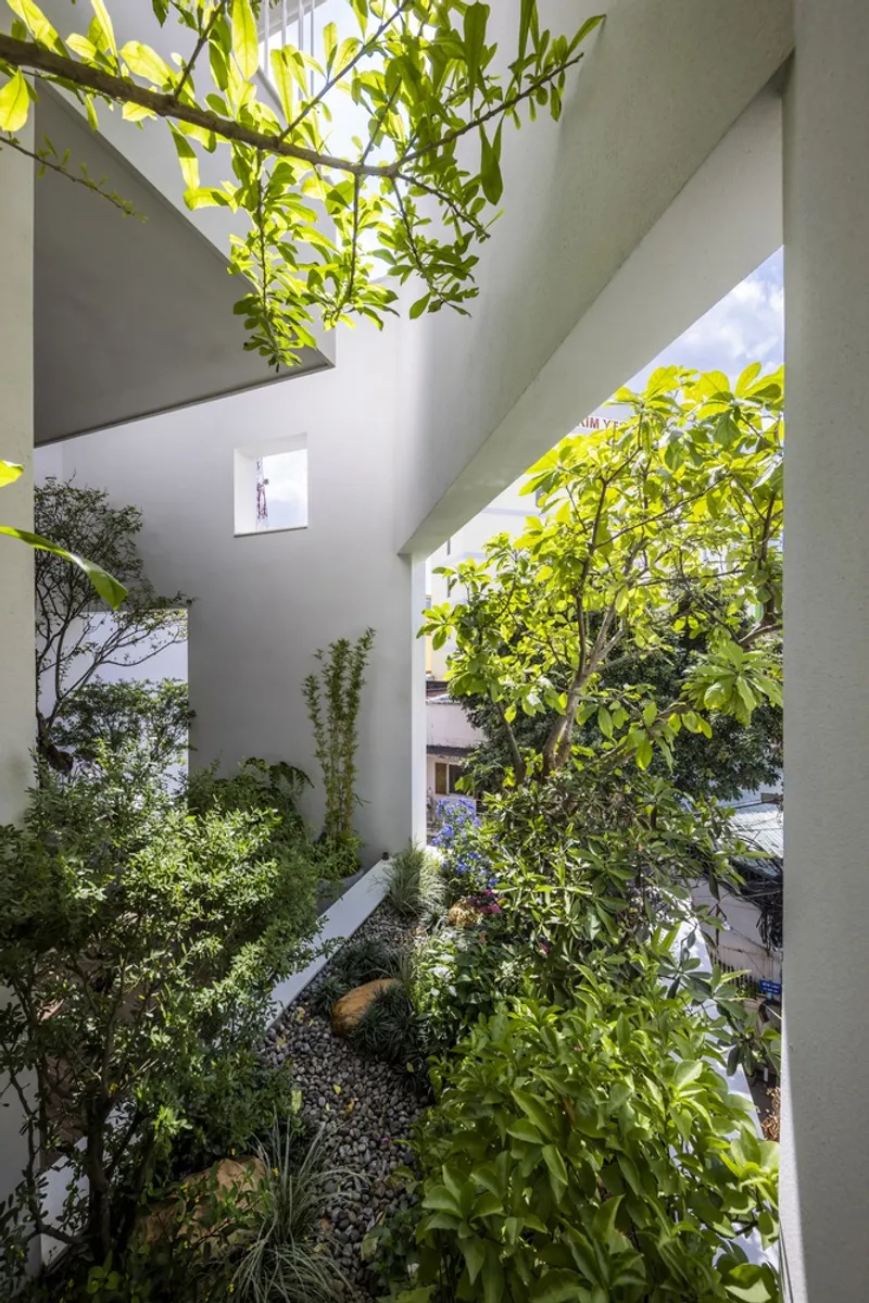 Interior courtyard with planted beds and trees beneath a skylit gabled ceiling