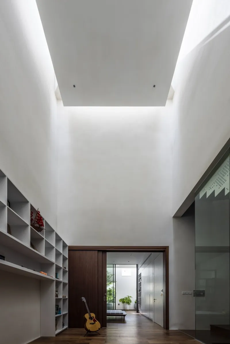 Corridor with recessed ceiling cove and built-in shelving leading to glazed rooms