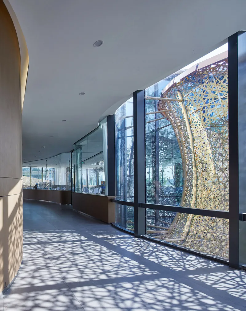 Interior corridor with perforated metal screens casting dappled shadows on polished floor