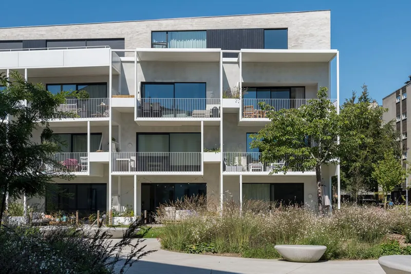 Front facade showing the tiered balconies framed by white columns with wildflower meadow planting below