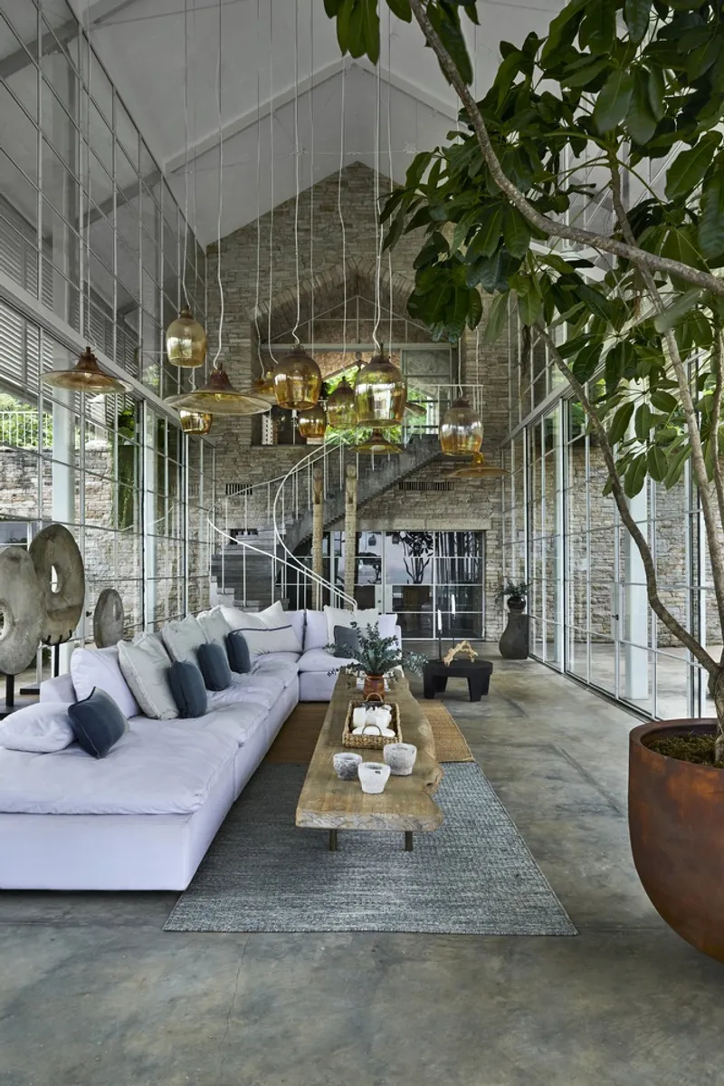 Double-height living space with brick vault, spiral stair, glass walls and a large potted tree