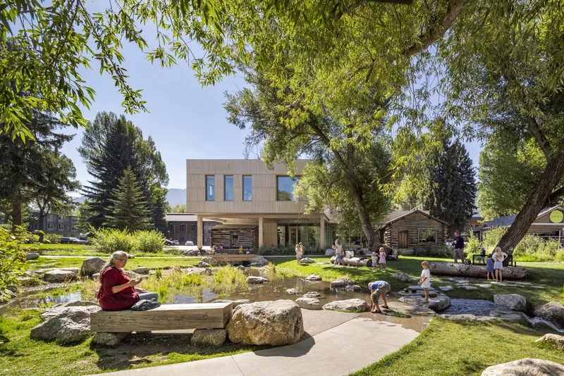 Rear courtyard with shallow water feature, stone seating, and children playing under dappled tree shade
