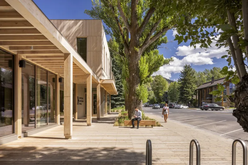 Covered walkway with timber columns and exposed ceiling joists framing the pedestrian sidewalk and street beyond