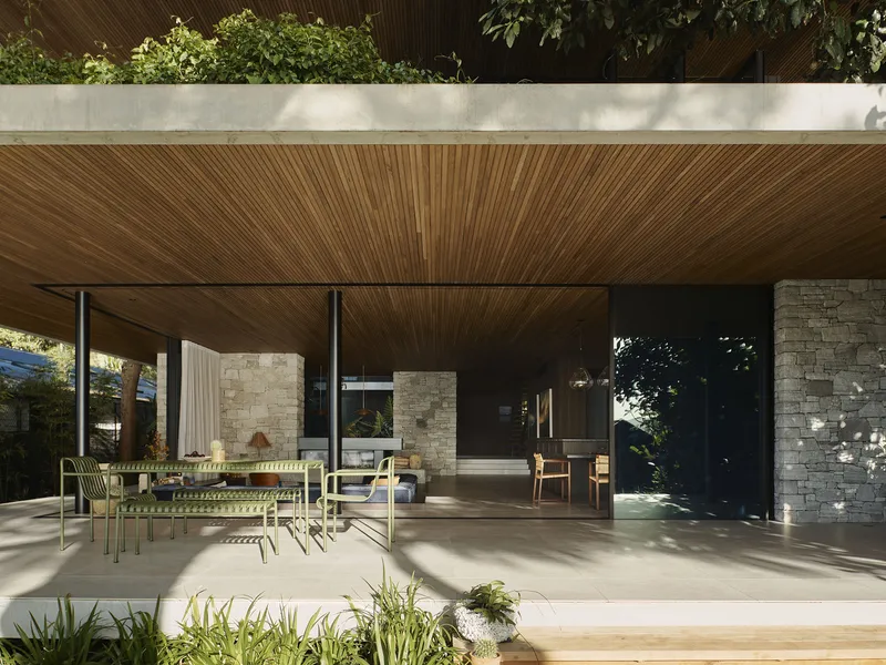 Covered outdoor terrace with timber slat ceiling and stone columns in dappled afternoon light