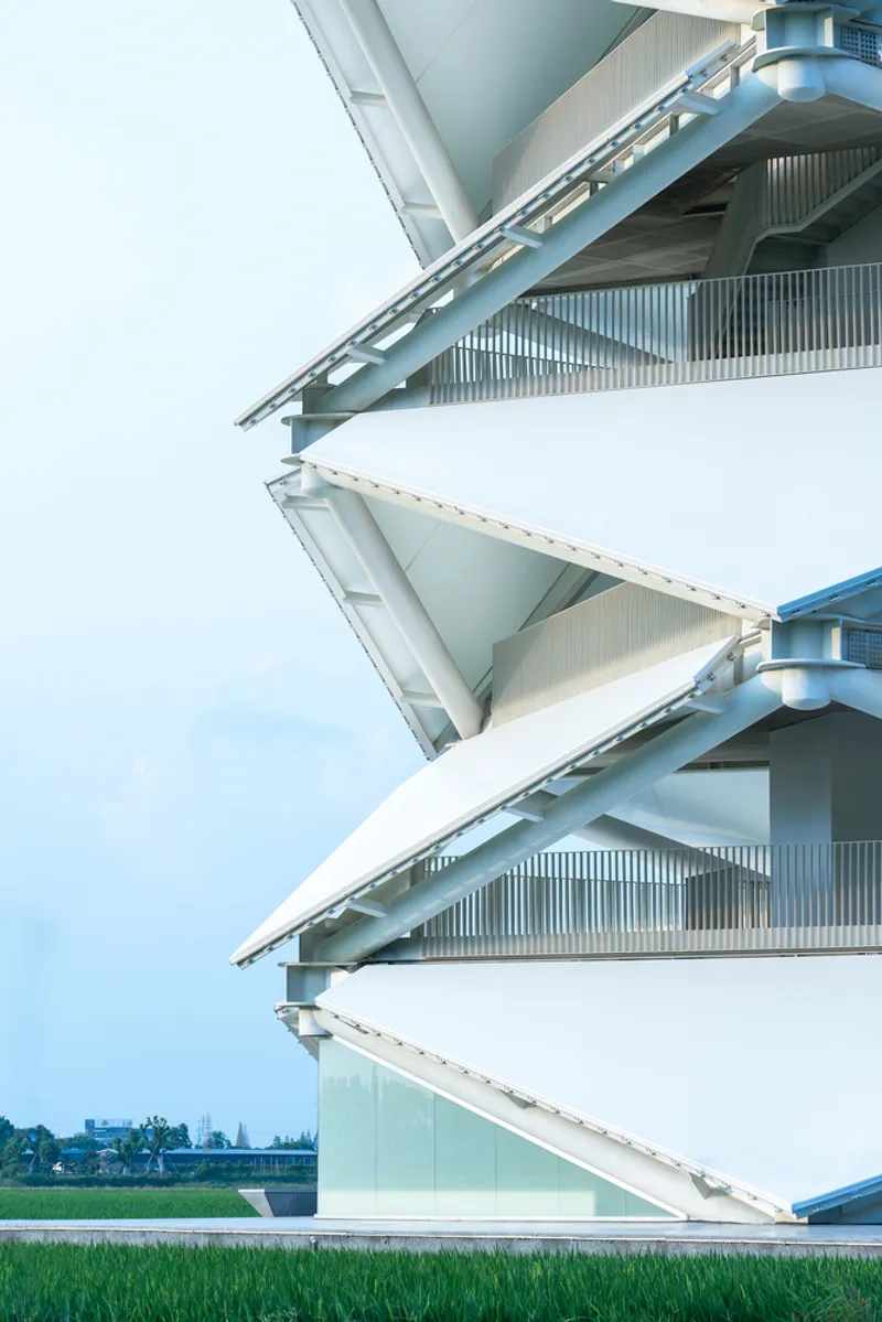 Close-up of the alternating triangular floor plates with corrugated metal balustrades and vertical louvers