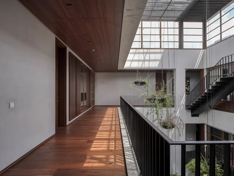 Upper floor corridor with timber ceiling and railing overlooking the planted courtyard below