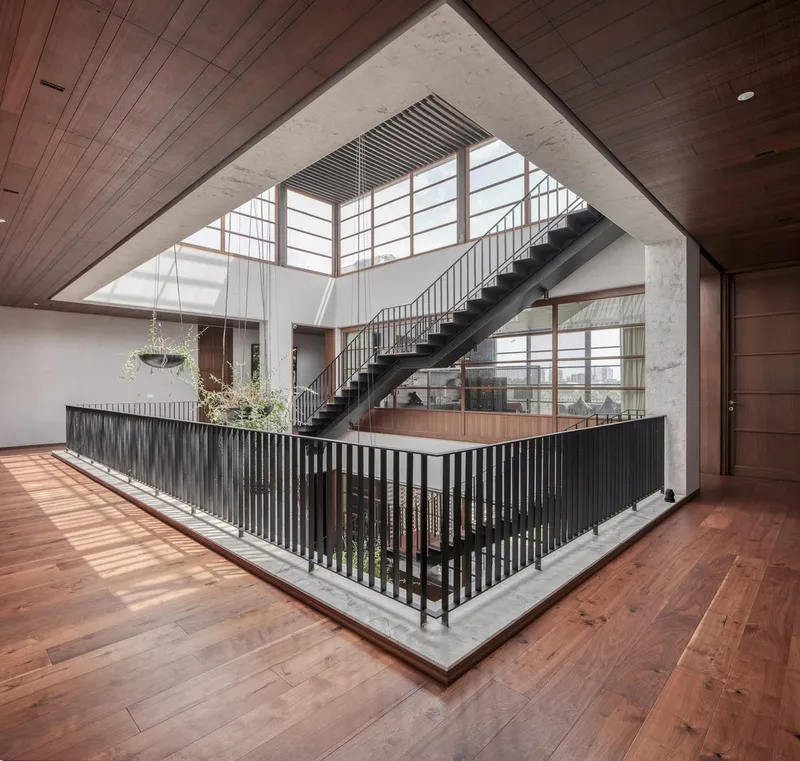 Double-height interior atrium with steel staircase and planted courtyard under clerestory skylights