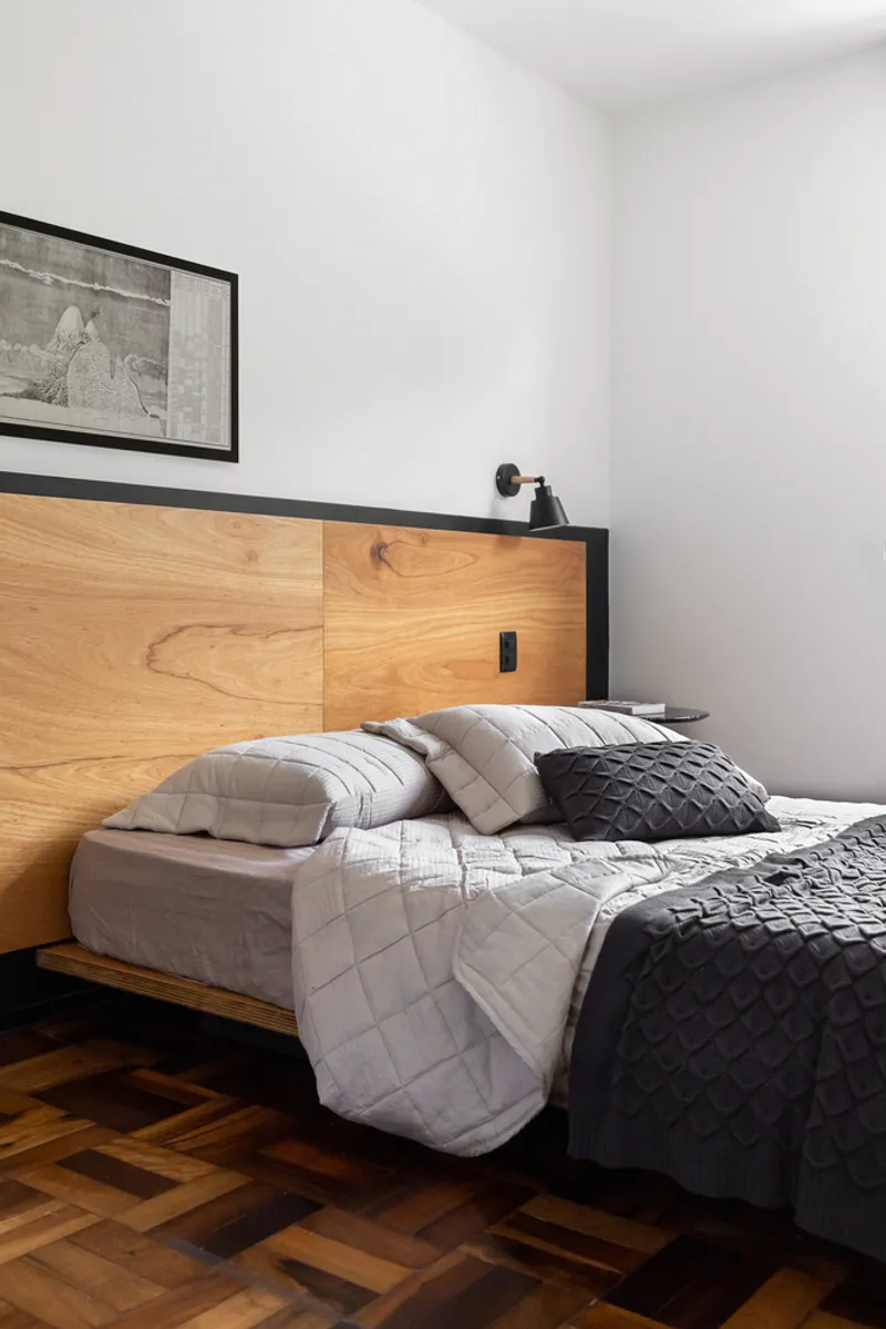 Bedroom with timber headboard featuring integrated lighting and parquet floor beneath grey bedding