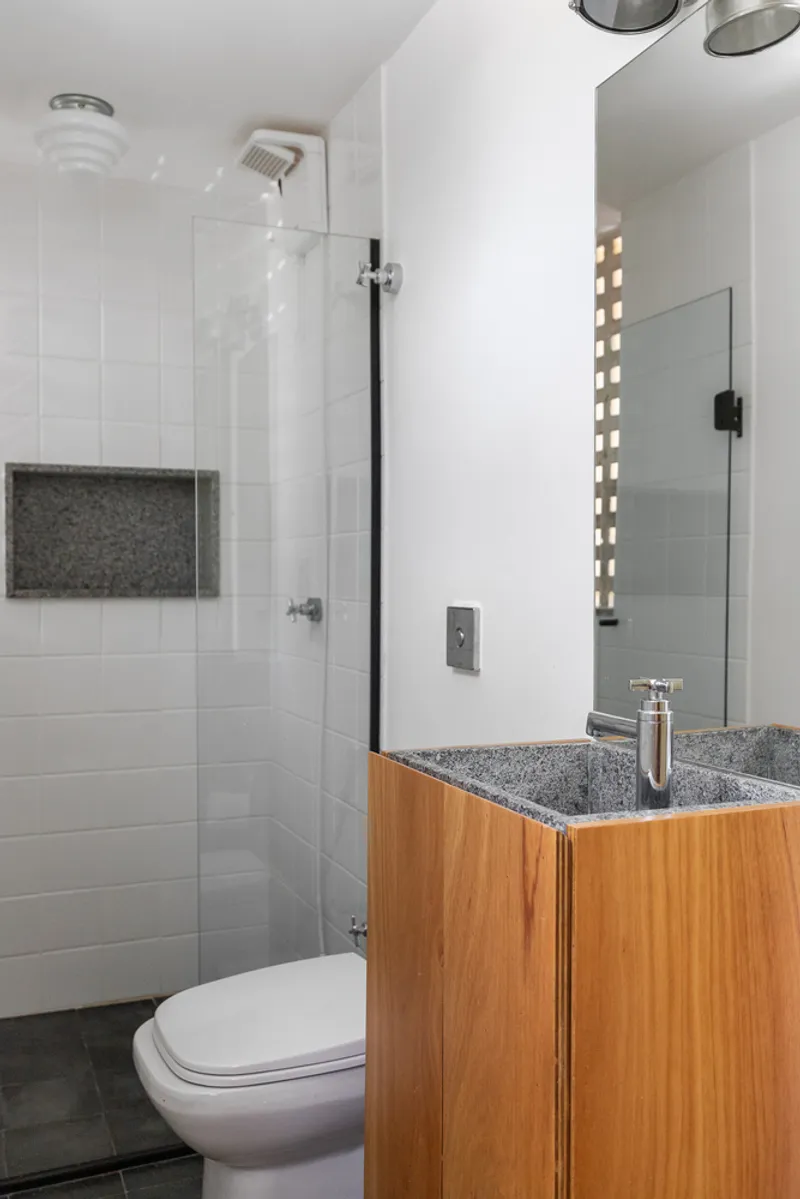 Compact bathroom with white subway tile shower, terrazzo-topped timber vanity and glass block light well