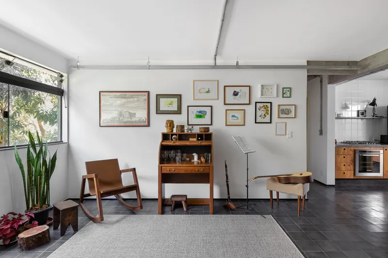 Living area with exposed concrete beam, timber furniture and potted plants beneath corner window