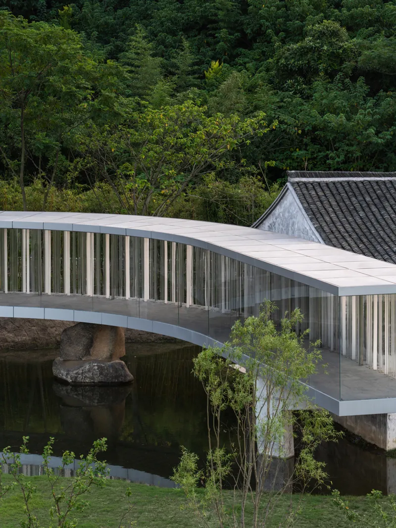 Side view of the curved bridge structure with vertical metal fins over water and stone outcrop
