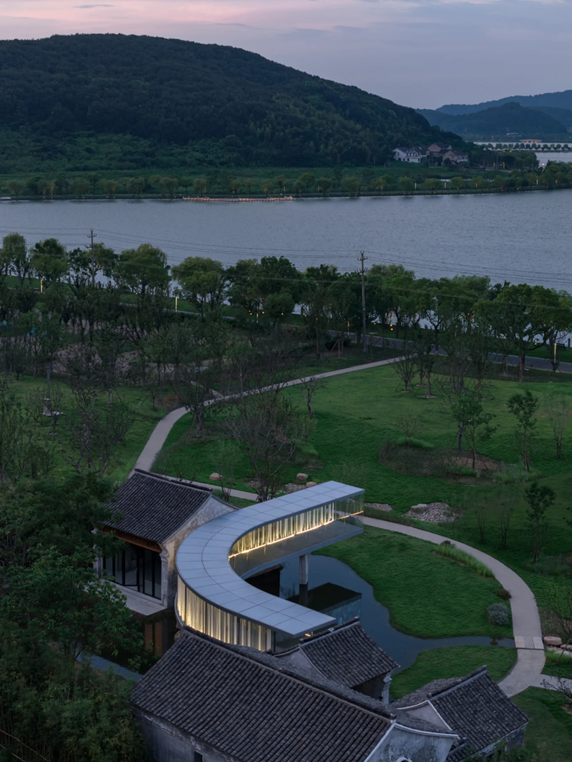 Domain Architects Weave a Curved Glass Corridor Between Two 1930s Houses on a Chinese Lakeshore