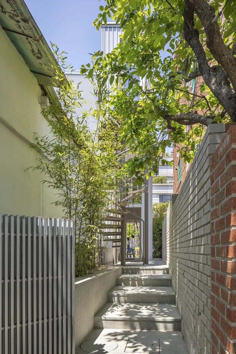 Narrow side passage with exterior stair flanked by vertical metal slats and planted bamboo