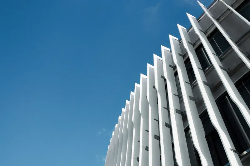 Angled view of white vertical blade sunshades projecting from the facade against blue sky