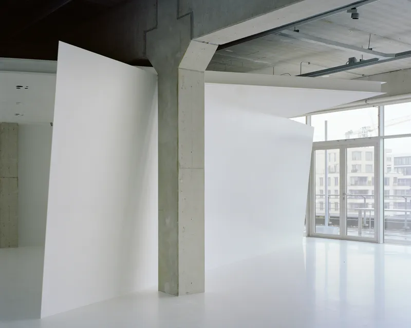 Exposed concrete column and waffle slab ceiling in a daylit interior with reflective floor