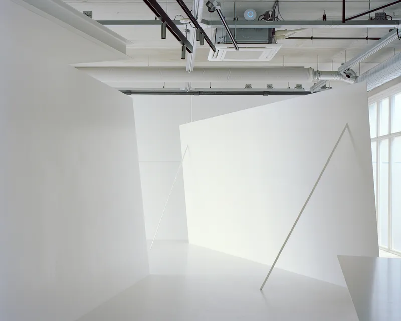 Freestanding white partition walls with diagonal shadows cast by window light