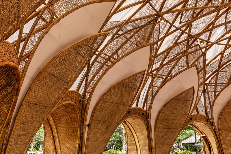 Interior view looking up at the vaulted bamboo ribs and woven rattan ceiling panels