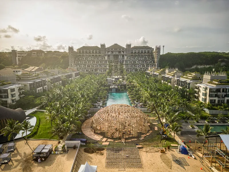 Long view of the bamboo pavilion with turquoise pool and residential buildings under overcast skies