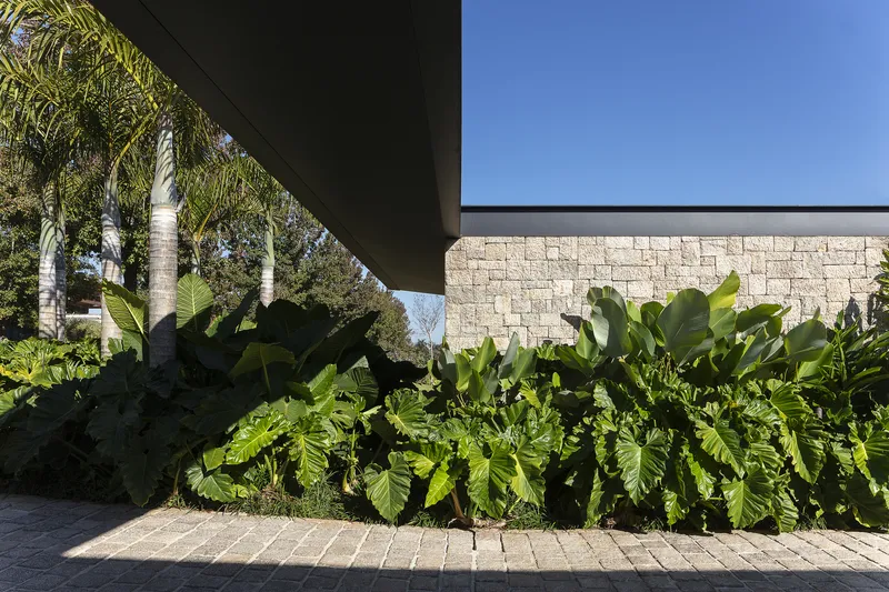 Stone block wall with planted bed of tropical foliage beneath the deep overhang
