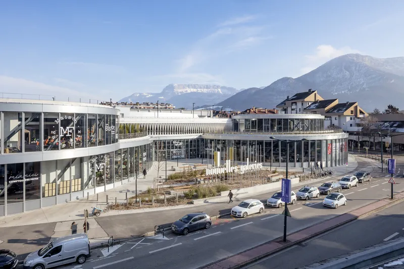 Aerial view of the curved glass and metal complex with mountains rising in the background