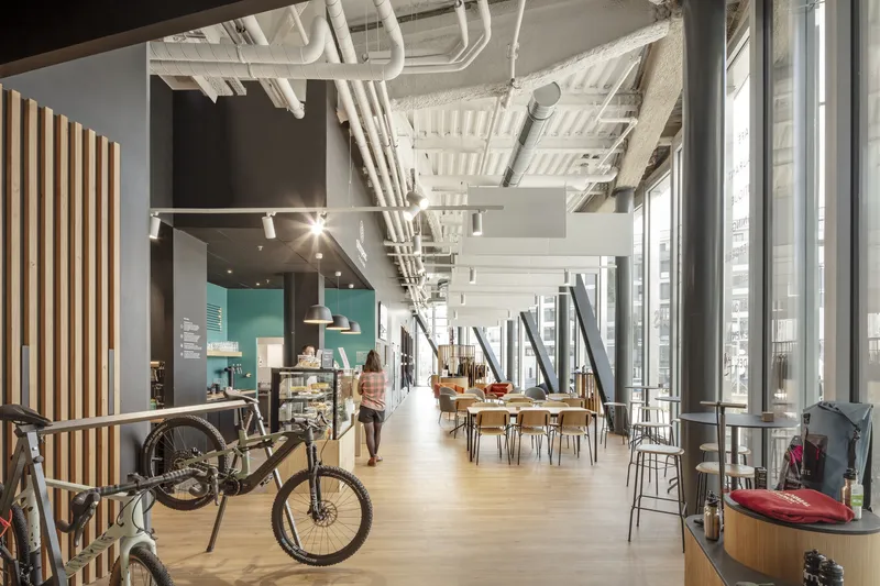 Interior corridor with exposed mechanical ducts and timber slat wall alongside a bicycle display