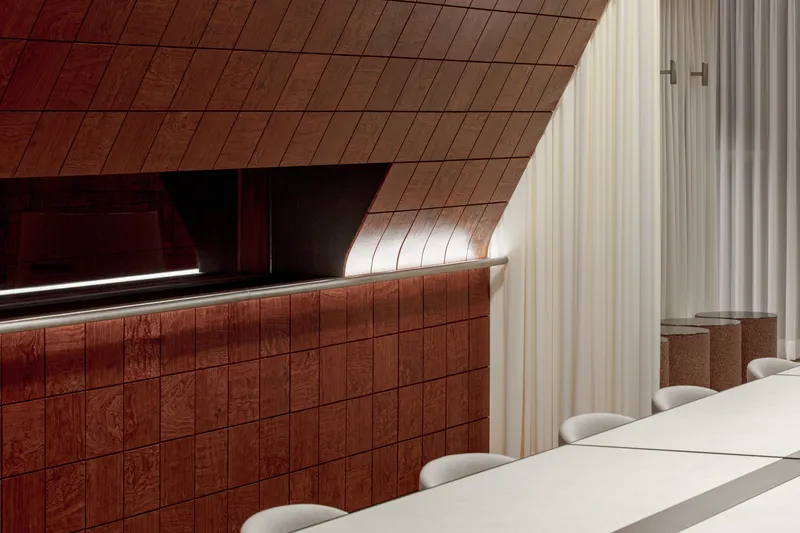 Red-tiled counter beneath angled soffit with linear lighting and adjacent white curtain panel