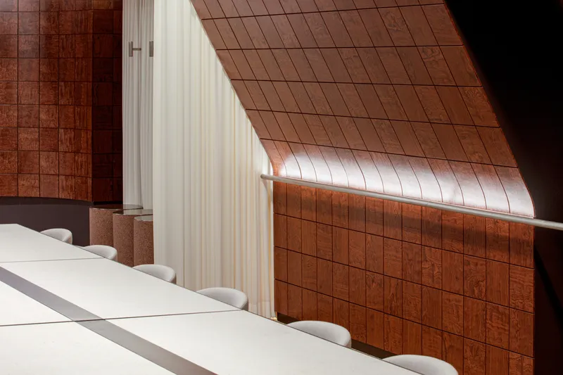 Angled red tile wall meeting white curtain with natural light streaming across the surface