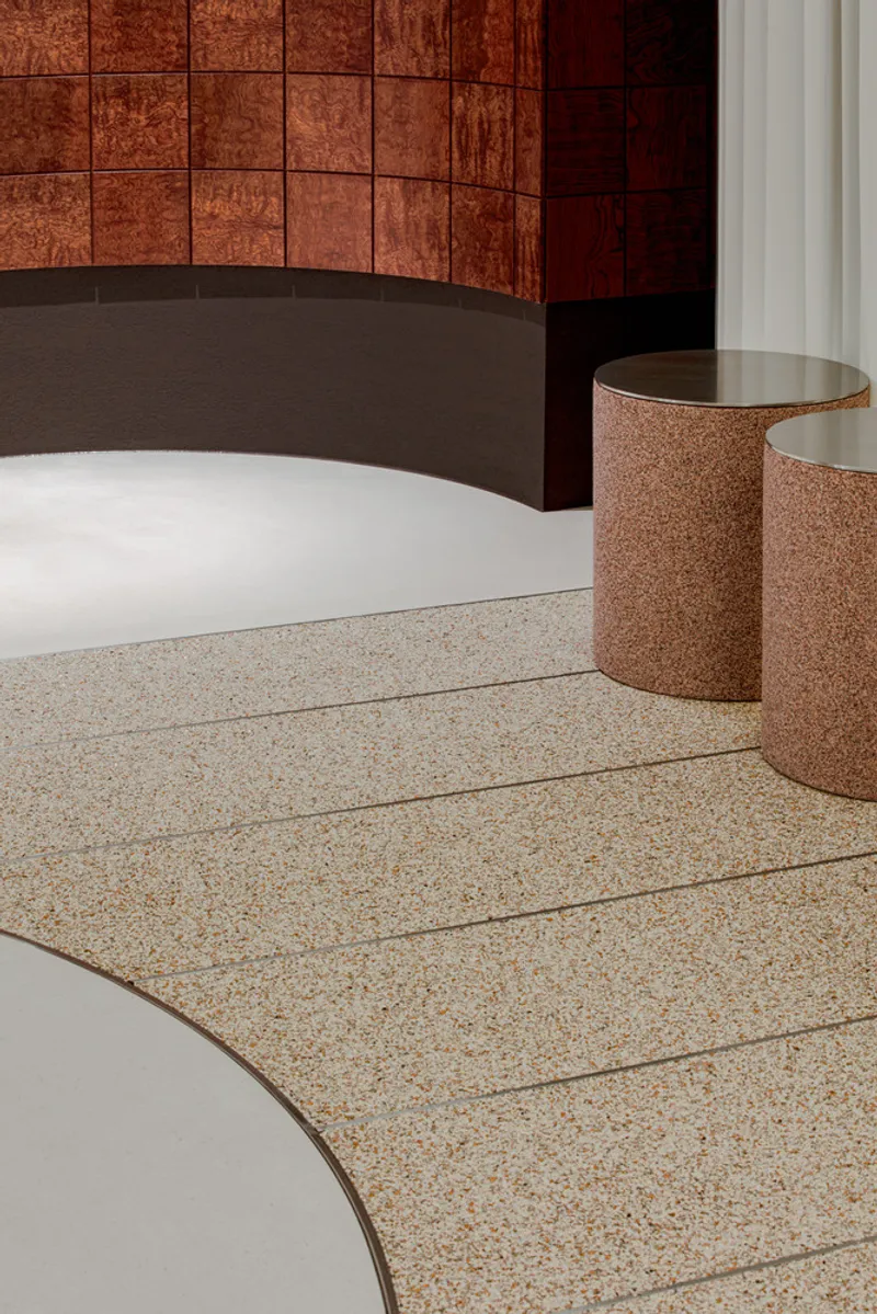Detail of terrazzo flooring meeting pink cylindrical objects and a curved white platform edge