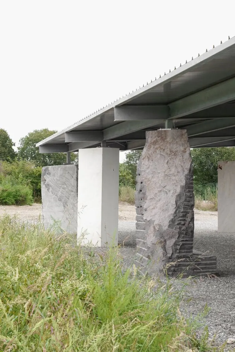 Angled view of the steel roof structure with saw-tooth edge resting on mixed concrete and brick columns