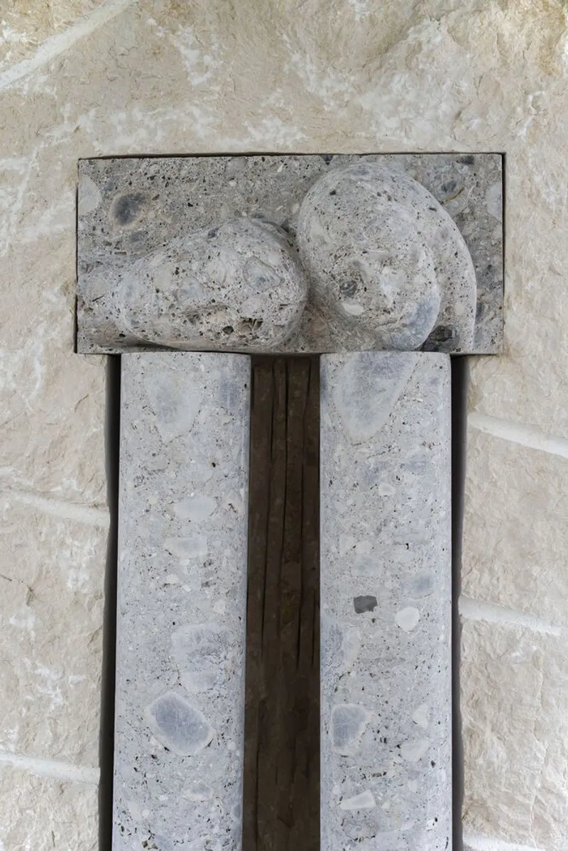 Close-up of a fossil-embedded concrete capital connecting dual vertical elements to a horizontal steel beam