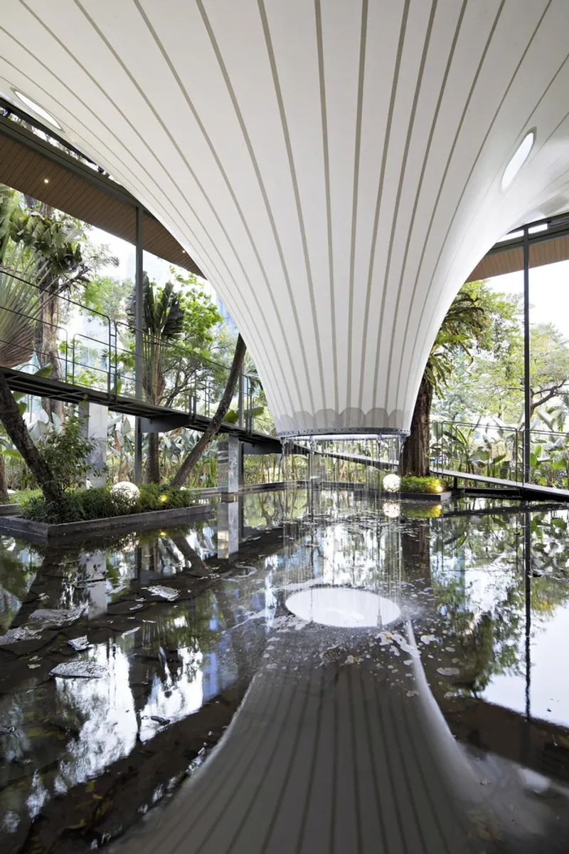 View beneath the tensile fabric canopy with radiating ribs over a reflecting pool and glass guardrails
