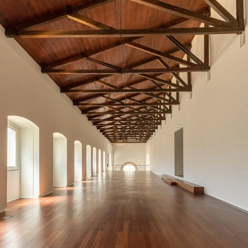 Gallery with exposed timber truss ceiling, arched window alcoves, and herringbone wood flooring