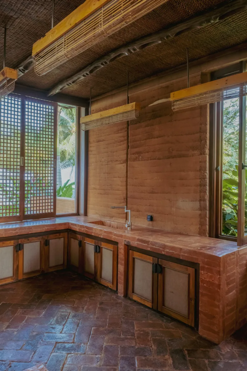 Kitchen counter with timber and fabric cabinetry below bamboo pendant lights and a woven ceiling