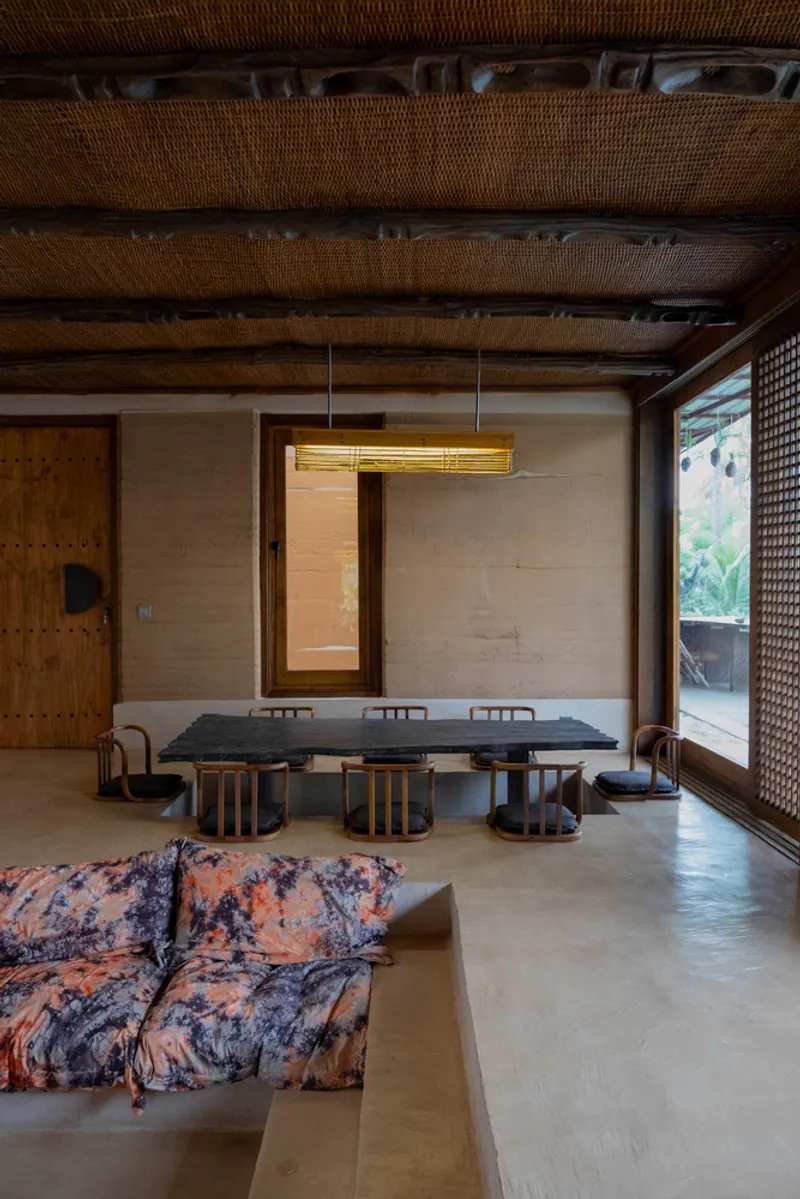 Interior dining area with woven ceiling and pendant light overlooking lattice-screened opening